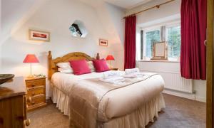 a bedroom with a large bed with red curtains at Priory Lodge in Windermere