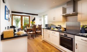 a kitchen with white cabinets and a dining room at Church View At Troutbeck in Windermere