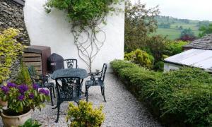 a patio with a table and chairs and flowers at Church View At Troutbeck in Windermere