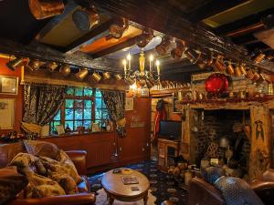 a living room with couches and a table and a fireplace at Wizards Thatch Medieval Styled Suites with Four Poster Beds in Alderley Edge