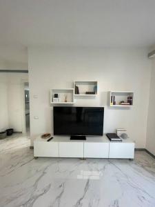uma sala de estar branca com uma grande televisão numa parede branca em Centoventinove em Carrara