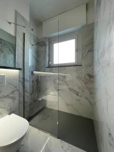 uma casa de banho com uma cabina de duche em vidro e um WC. em Centoventinove em Carrara