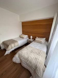 Hermoso departamento en playa Frutillar Bajo في فروتيلار: غرفة نوم بسريرين وجدار خشبي