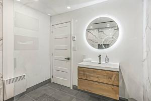 a white bathroom with a sink and a mirror at Cheerful 4 bedroom home with inground heated pool in Prévost