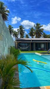 una casa con una piscina con una tabla de surf en Village dos Coqueirais en São Miguel do Gostoso