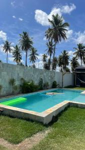 a swimming pool in a backyard with palm trees at Village dos Coqueirais in São Miguel do Gostoso