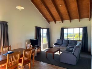 uma sala de estar com um sofá e uma mesa em Black Bream Point Cabins em Narooma