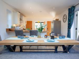 a wooden table in a living room with a kitchen at Crosshill Cottage in Honiton