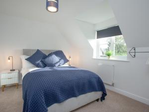 a bedroom with a blue and white bed and a window at Crosshill Cottage in Honiton