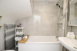 Dunstan House Luxury Holiday Home with free parking في أوكسفورد: حمام أبيض مع حوض ومغسلة