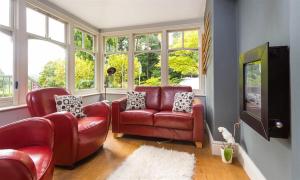 a living room with two red chairs and a tv at The Boundary in Windermere