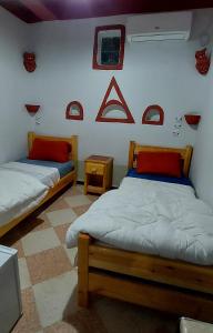 two beds in a room with red accents on the wall at Dar Agham Akbou in Timimoun