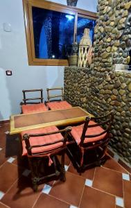 a table and chairs in a room with a stone wall at Dar Agham Akbou in Timimoun