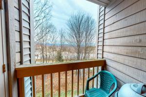 a balcony with a blue chair and a view of the woods at Ober Tal Getaway in Stratton