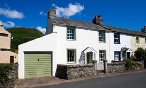 a white house with a green garage at Kent Cottage in Cockermouth
