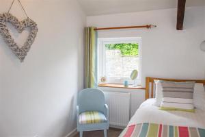 een slaapkamer met een bed, een stoel en een raam bij Four Seasons Cottage in Ambleside