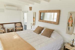 a bedroom with a white bed and a mirror at Laguna Garzón Lodge in José Ignacio