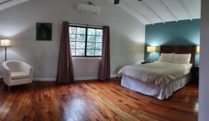 um quarto com uma cama, uma cadeira e uma janela em Santa Cruz Cabins em Santa Elena