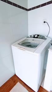 uma máquina de lavar roupa branca num quarto branco em Casa Confortável, 3 Quartos, Ar Condic. 300 Mega, Taubaté em Taubaté