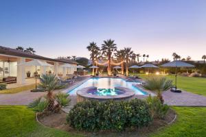 a backyard with a swimming pool with tables and umbrellas at Strut Oasis 70 - Play, Relax, Walk to Coachella Festival! in Indio