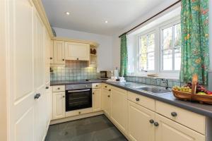 une cuisine avec des armoires blanches, un évier et une fenêtre dans l'établissement Bank Foot, à Ambleside 10 autres photos