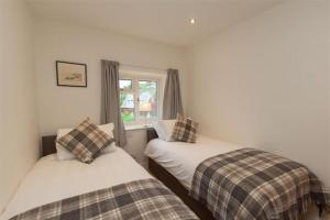 two twin beds in a room with a window at Mylnbeck in Windermere