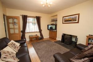 a living room with a leather couch and a television at Bleaberry Cottage in Penrith