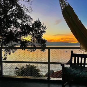 a view of the ocean at sunset from a hammock at Casa pé na areia para até 14 pessoas em bombinhas in Bombinhas