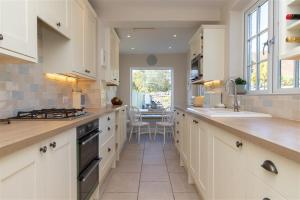 a large kitchen with white cabinets and a table at Crozier Cottage in Ambleside