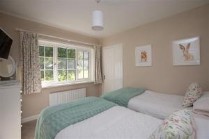 a bedroom with two beds and a window at Crozier Cottage in Ambleside