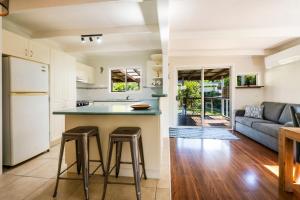 cocina y sala de estar con encimera y taburetes en Fins Hideaway, en Iluka