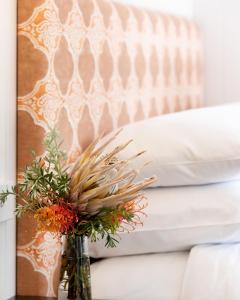 a vase with flowers on a table next to a bed at Jackson Ranch by Bannisters in Bawley Point
