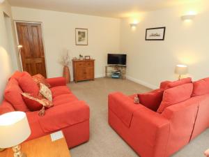 a living room with two red couches and a television at Kirkstones in Keswick