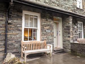 a wooden bench sitting outside of a stone building at Hazeldene in Ambleside