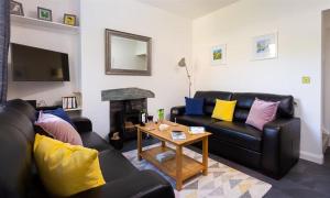 ein Wohnzimmer mit Sofas, einem Tisch und einem Kamin in der Unterkunft Fell Cottage in Ambleside
