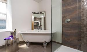 a bathroom with a tub and a shower with a mirror at Fell Cottage in Ambleside +14 photos