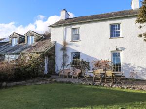 a white house with chairs and a yard at Robin Cottage in Troutbeck