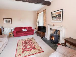 a living room with a red couch and a fireplace at Robin Cottage in Troutbeck