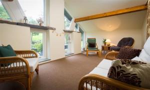 a living room with wicker furniture and windows at Hawkshead Hall in Hawkshead