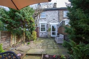 a stone house with a patio and an umbrella at Swallow's Nest in Bowness-on-Windermere