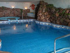 a large swimming pool in a hotel with a rock wall at Apartment in the middle of nature in Santa Cruz de Tenerife in San Miguel de Abona