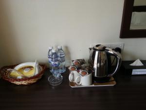 a table with a coffee pot and a basket of water at Goodhope Hotel Gurney, Penang in George Town