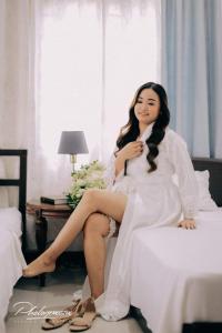 a woman in a white dress sitting on a bed at SOFIATEL Rooms in Santa Maria