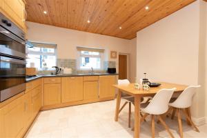 uma cozinha com uma mesa de madeira e cadeiras brancas em Gable End em Keswick