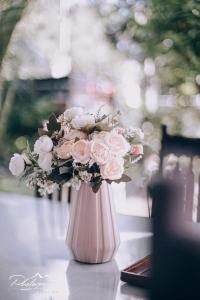 een roze vaas gevuld met roze en witte bloemen bij SOFIATEL Rooms in Santa Maria