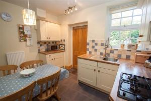 a kitchen with a sink and a table with chairs at Briardale Cottage in Ambleside