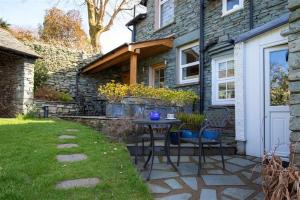a patio with two chairs and a table in front of a house at Briardale Cottage in Ambleside