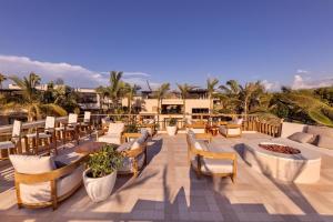 a patio with chairs and tables and palm trees at Kimpton Mas Olas Resort and Spa, an IHG Hotel in El Pescadero