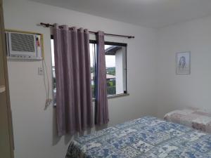 a bedroom with a window with purple curtains at Apartamento em guarajuba 200m da praia in Camaçari