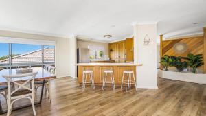 a kitchen and living room with a counter and stools at Emerald Escape Lighthouse Beach in Port Macquarie